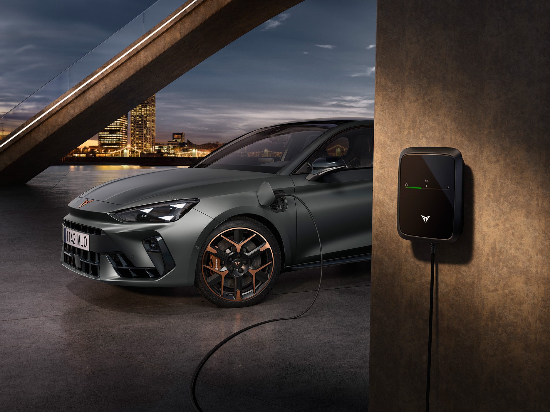 Une CUPRA Leon stationnée dans un environnement urbain la nuit, en cours de recharge.