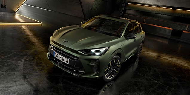 A green Cupra Terramar SUV is parked in a dark, industrial garage. The car is the main subject, with its front and passenger side visible.