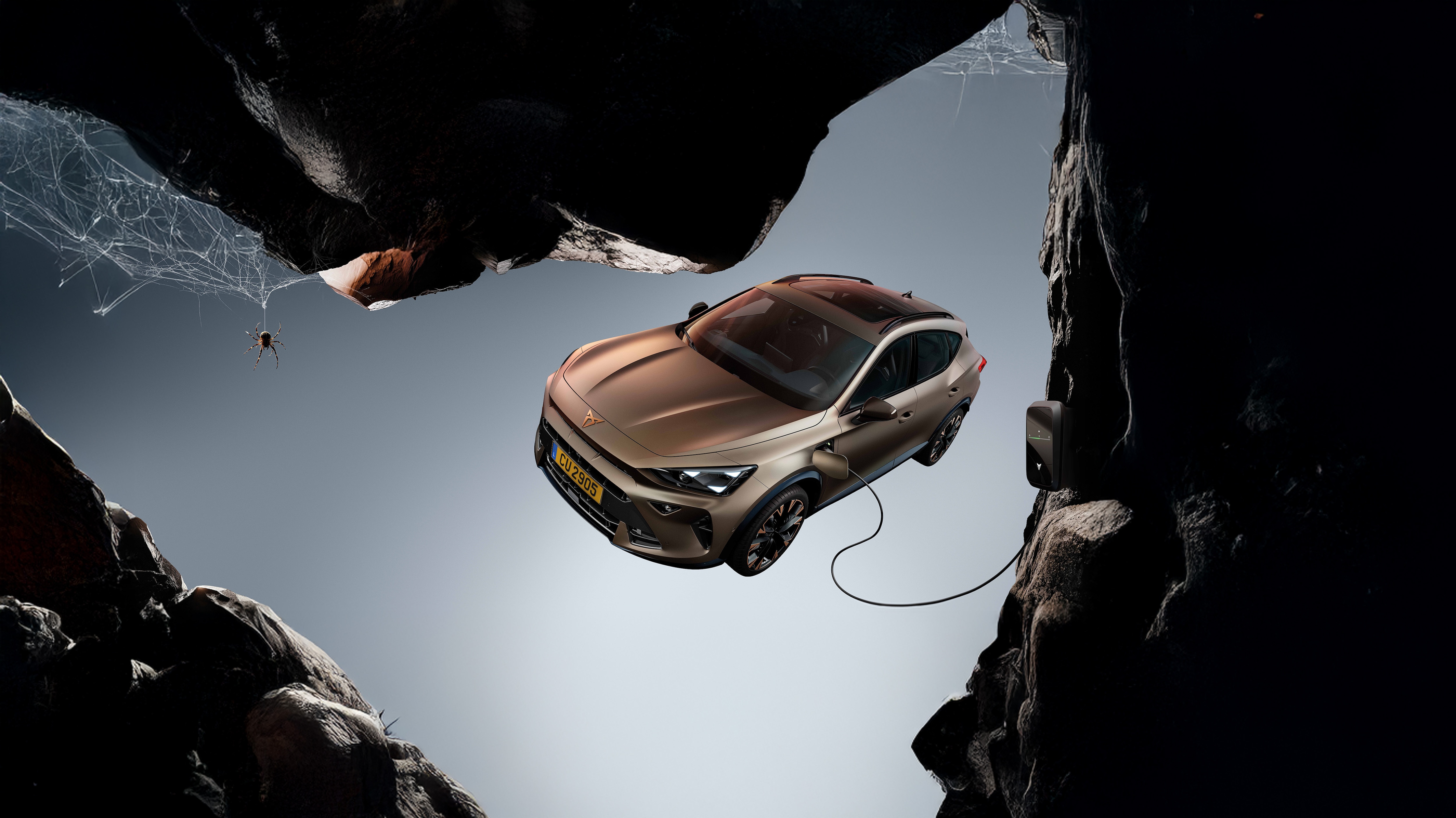 La CUPRA Plug-in aux couleurs de Cooper flotte dans les airs devant l'entrée d'une grotte où une araignée tisse sa toile.