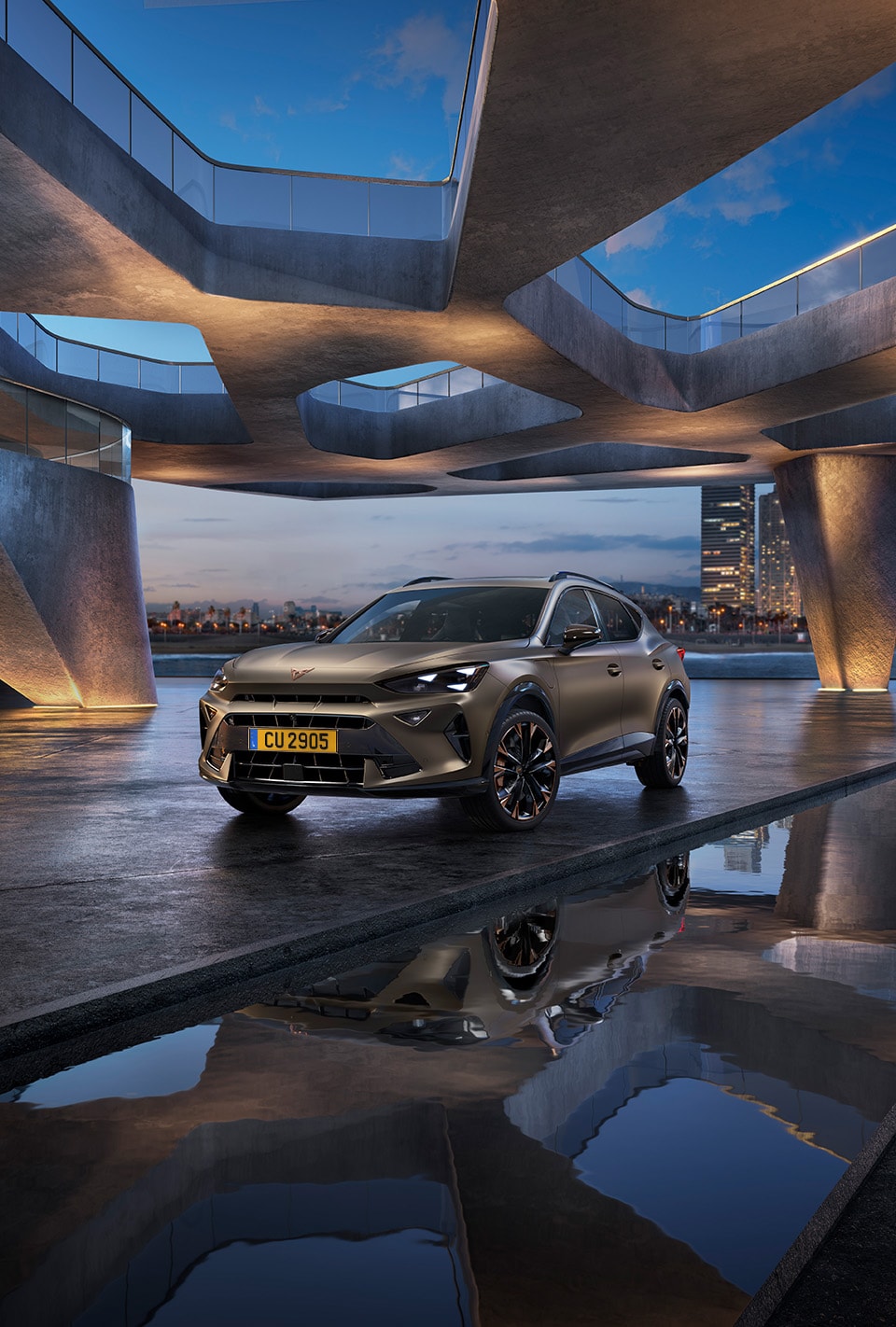 three quarter front view of new cupra Leon 2024 in Enceladus grey and architectural structure, parked on smooth cement, backdrop of Barcelona cityscape.